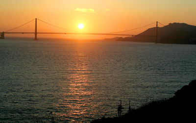 [ Sun setting behind Golden Gate Bridge ]